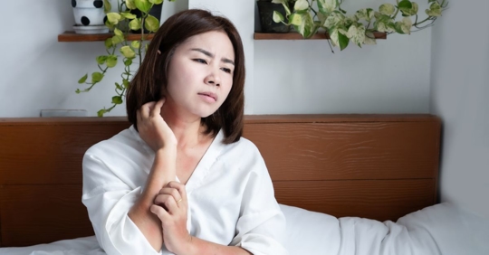 woman itching herself in bed